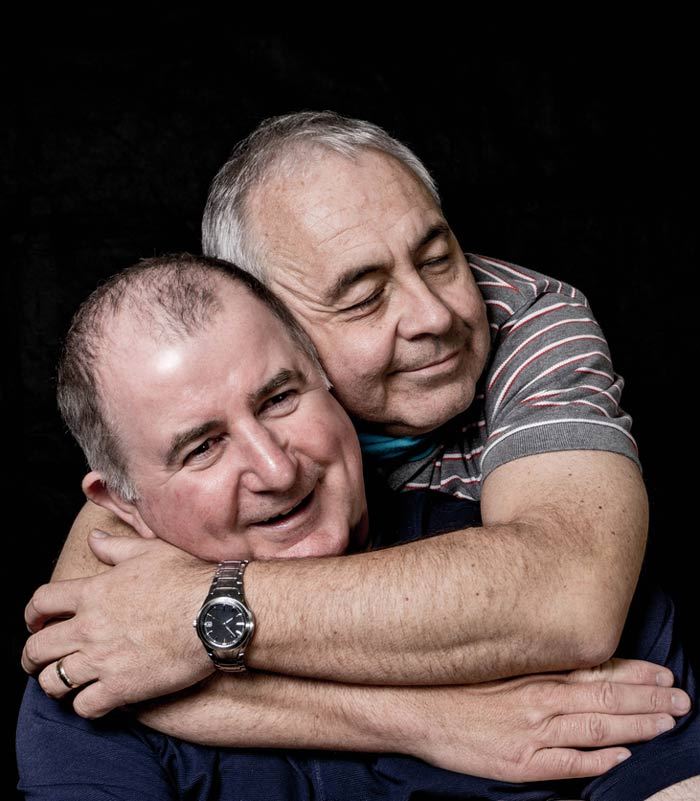 Photo of middle aged gay couple embracing